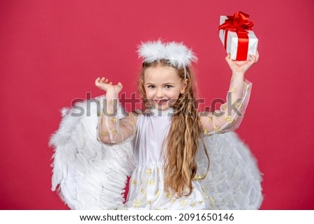 Happy smiling angel girl, isolated on red. Playful angelic little child. Christmas kids.