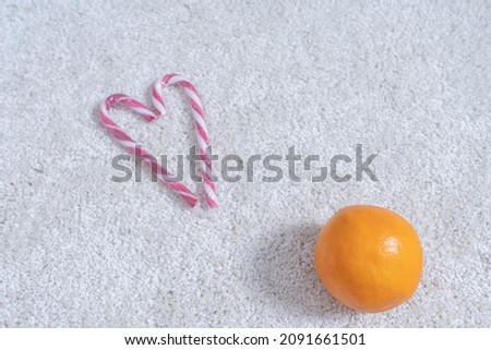 Heart made of lollipops and oranges on the carpet. Concept postcard for Christmas, New Year greetings. There is a place for text