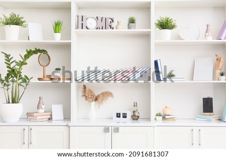 Shelf unit with books, houseplants and decor, closeup Royalty-Free Stock Photo #2091681307