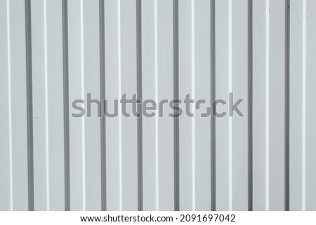Gray iron construction profiled sheet with vertical stripes. Textured background. Corrugated building material for fences and roofs.