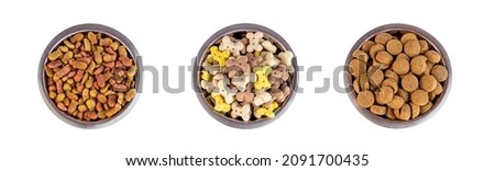 Top view of brown biscuit bones and crunchy organic kibble pieces for dog feed in a metal bowl set isolated on white background. Healthy dry pet food Royalty-Free Stock Photo #2091700435