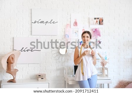 Female fashion designer with cup of coffee in studio