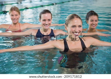 Smiling female fitness class doing aqua aerobics in swimming pool at the leisure centre Royalty-Free Stock Photo #209171812