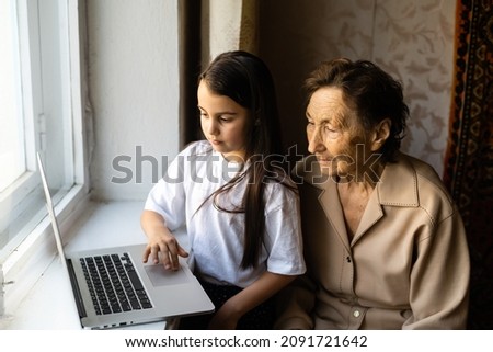 very elderly great-grandmother and granddaughter with laptop online