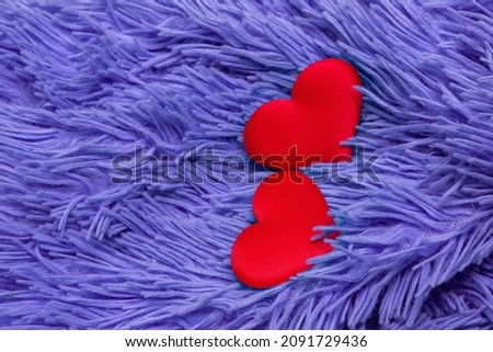 two juicy bright red textile hearts on a fleecy woolen blue very peri plaid; for the design of valentines and wedding invitations; there is a place to insert text