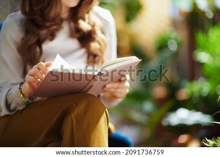 Green Home. Closeup on female with long wavy hair with book in the house in sunny day. Royalty-Free Stock Photo #2091736759
