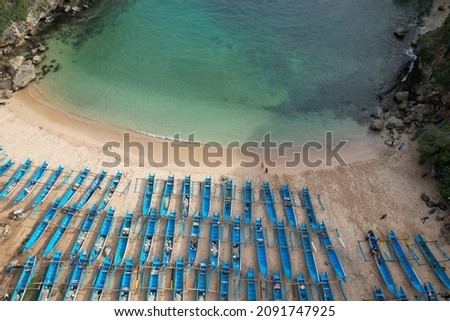 aerial photography of white sandy tropical beach with blue fishing boats lined up neatly on the shore. clear watery beach, green tosca. Pantai Ngrenehan in Gunungkidul Yogyakarta Indonesia. 