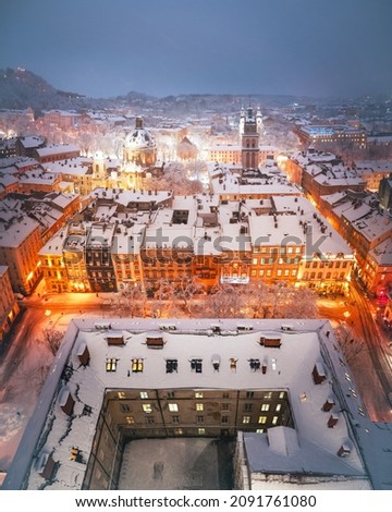 Gorgeus cityscape of winter Lviv city glowing by city lights with roofs covered by snow from top of town hall, Ukraine, Europe. Landscape photography