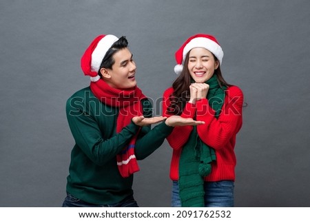 Young handsome Asian man surprising his girlfriend on Christmas,  studio shot in isolated gray background