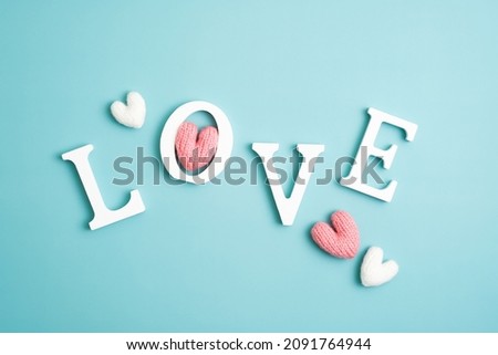 Happy Valentines Day creative layout. Love word and knitted hearts on blue background.