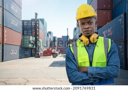 workers man engineering standing with confident with blue working suite dress and safety helmet. manual worker in front container background. Concept of smart industry worker operating.