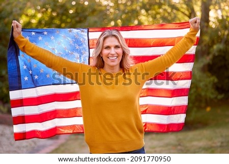 Portrait Of Patriotic American Woman Outdoors Holding Stars And Stripes Flag