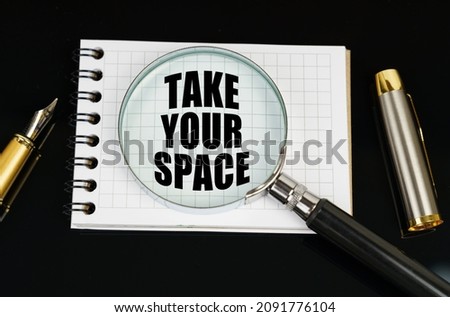Business and finance concept. On a black surface there is a pen, a notebook and a magnifying glass. The inscription in the notebook - TAKE YOUR SPACE