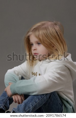 Studio portrait of toddler girl in jeans and hoodie	