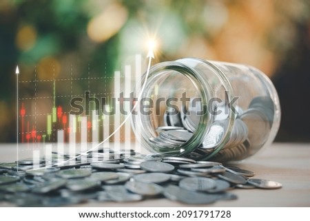 Saving concept, a glass jar with coins inside and a lot of coins for financial and business background, keep money for education, learning, funds, bonds, dividends, investments in future. Royalty-Free Stock Photo #2091791728