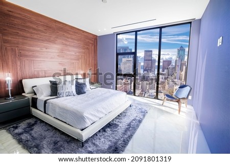 Modern and contemporary bedroom in Seattle with views of the financial district of the city. Condo or Hotel accommodation. Very Peri colored walls. Royalty-Free Stock Photo #2091801319