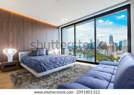 Modern and contemporary bedroom in Austin Texas with views of the financial district of the city. Condo or Hotel accommodation. Very Peri colored bed and couch. Royalty-Free Stock Photo #2091801322