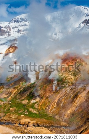 View of gas and steam geyser eruptions of the Stained glass wall in the Valley of Geysers. Ð¢ypical landscape with geyser emissions of water, steam and gases in the Valley of geysers in Kamchatka.  Royalty-Free Stock Photo #2091811003