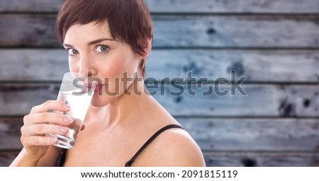 Composite image of caucasian woman drinking water from a glass against wooden background. healthy lifestyle concept
