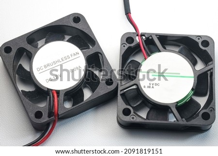 DC brushless fan with 5 volt and 12 volt DC. Mini cooling fan made of black plastic complete with cables on isolated white background. Royalty-Free Stock Photo #2091819151