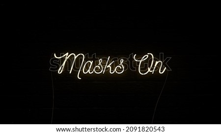 Neon sign on a brick wall background saying Masks on warning people to put on a mask due to the coronavirus  covid-19 pandemic, 