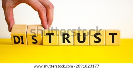 Distrust or trust symbol. Businessman turns wooden cubes, changes words 'distrust' to 'trust'. Beautiful yellow table, white background. Business and distrust or trust concept, copy space.