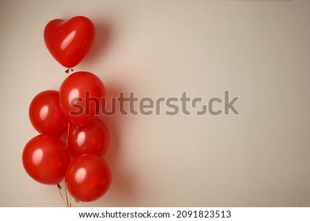A bouquet of red balloons on a beige wall background. Picture for Valentine's Day. The concept of gifts and lovers. High-quality photography