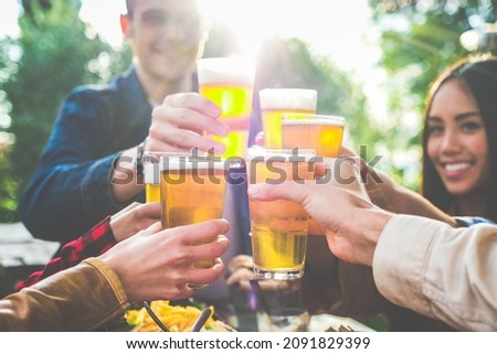 Group of multiethnic friends drinking beer at outdoor pub restaurant - Young people enjoying drinks during happy hour at terrace bar toasting with beers and chatting - Friendship concept Royalty-Free Stock Photo #2091829399