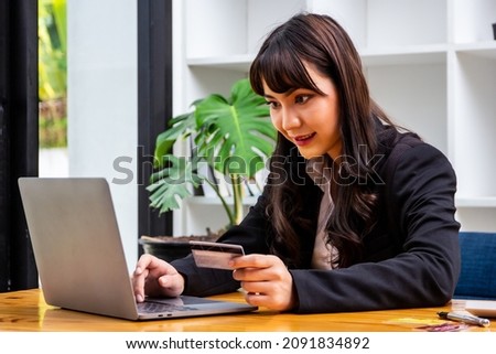 Businesswoman using credit card and laptop to buy stocks online, woman holding plastic credit card and using laptop to shop online, online shopping and stock trading concept.
