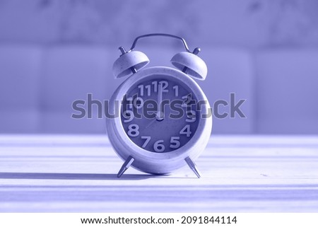 Close up clock for decoration at 8 o'clock stands on a wooden texture with copy space. Very peri toned image. Copy space