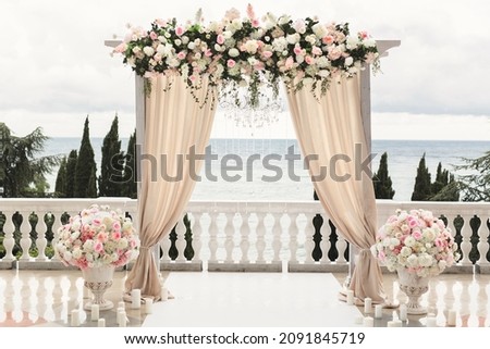 The wedding arch decorated with flowers stands in the luxurious area of the wedding ceremony. Royalty-Free Stock Photo #2091845719