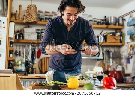man blogger taking photo of salad in his kitchen