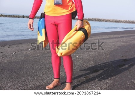 surfer on the seashore with a yellow lifebuoy, marine recreation and safety theme