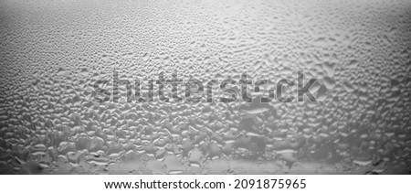 after Rain drops on the window glass. gray sky backdrop. white and black  background. condensation on the transparent glass. 