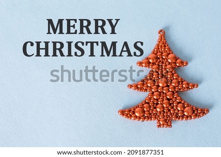 Merry Christmas text on the background next to the red Christmas tree decoration