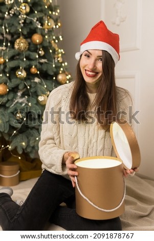 The young smiling girl holds gold gifts near Christmas festive tree