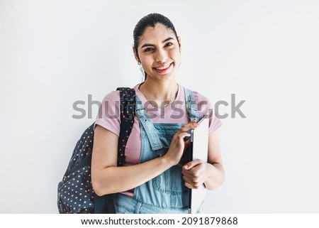 Young latin student woman holding notebooks laughing with glasses over isolated grey background in Latin America