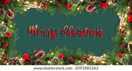Christmas decorated and illuminated garland frame on green background with red written text Merry Christmas.