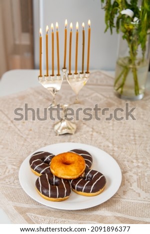 A lit hanukkah with everyone on the table next to donuts and a vase of flowers. Vertical photo