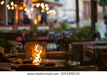 blurred photo of street cafe terrace decorated with flame heate, evening street lights, fcozy mood Royalty-Free Stock Photo #2091898135