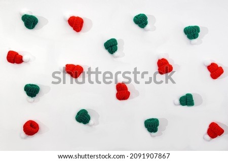 A seamless pattern made of red and green hats with white pompoms on white background. Design for background or backdrop. Creative concept for winter holidays advertisement or banner.