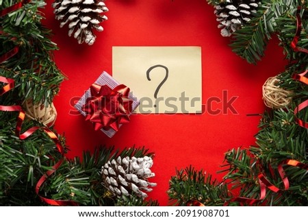 Gift box with a red bow on red background with question sign, Christmas unboxing theme. What to give on a new year.