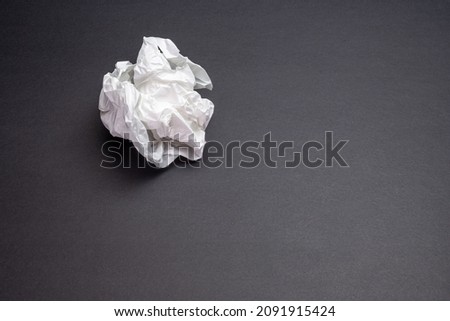 A piece of crumpled white paper on a black background in the form of a ball. space for printing. background picture.