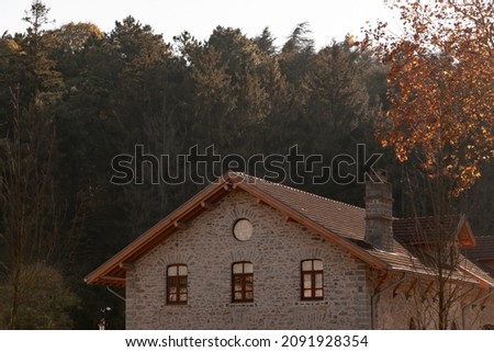 A beautiful huge house. Triangle roof. Stone house in autumn season. Soft, orange colors. 