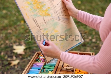 Woman drawing with soft pastels outdoors, closeup