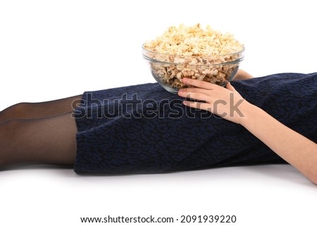 Girl lies on the floor with a bowl  of popcorn. Isolated on white. High resolution photo.