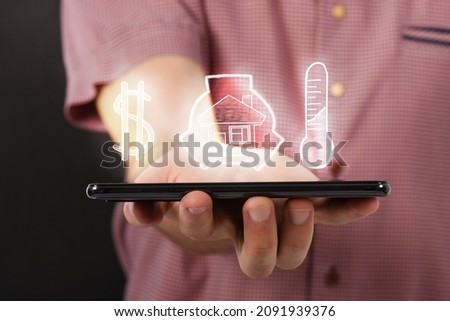 Man hand holding horizontal the black smartphone with image of cheap, comfortable and safe home concept . isolated on black background. High resolution photo. 