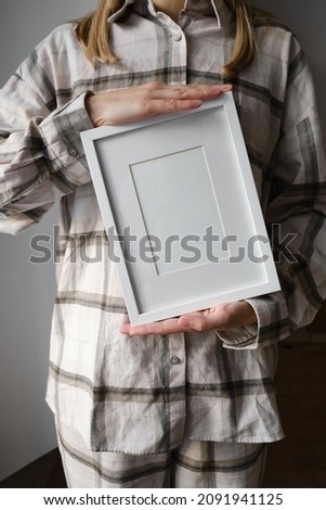 White frame for text in the hands of a girl close-up. Space for inscriptions and advertisements. Stylish piece of furniture