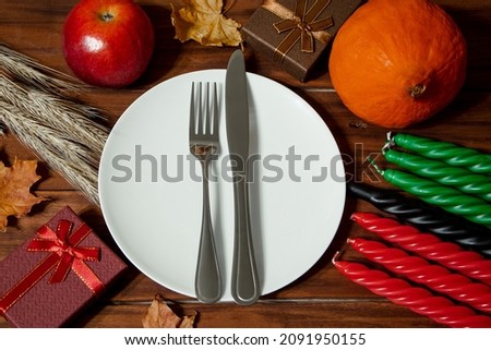 Festive table setting for African American Kwanzaa celebration. Symbols of African heritage. Seven candles in red, black and green. Harvest and gifts on wooden background.