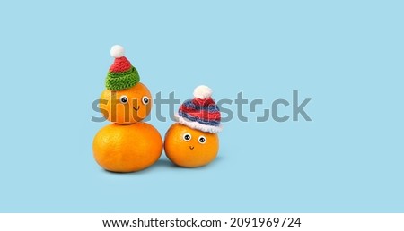 two cute snowmans made of Tangerines with knitted hats, smiles, googly eyes. Friendly Face funny character. kawaii style. Christmas, New Year holidays, festive winter season